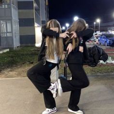 two young women standing next to each other in front of a parking lot at night