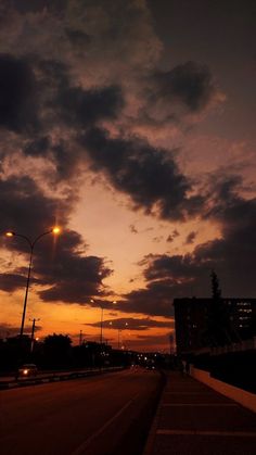 the sun is setting over an empty street