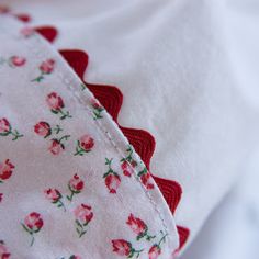 a close up of a white shirt with pink flowers on it and red trimmings