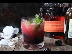 a glass filled with ice and blackberries on top of a wooden table