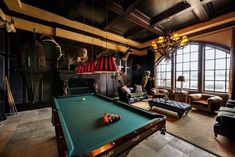 a pool table in the middle of a living room with lots of windows and furniture