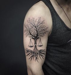 a man's arm with a tree and balance scale tattoo on it