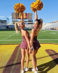 two cheerleaders holding up pom - poms in the air