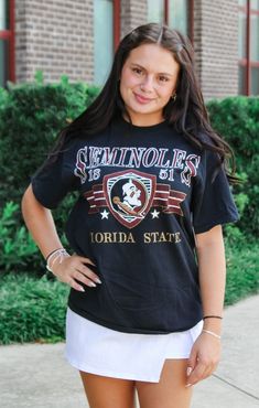 Get ready to rock your game day look with The FSU Pep Rally Thrifted Tee! This unique shirt features a vintage, lived-in feel and a bit of distressing for a cool, preppy vibe. Size up for the perfect oversized look and get ready to rally in style. Details: *OFFICALLY LICENSED* Distressed, Thrifted Knit Tee 100% Preshrunken Cotton Crew Neckline, Short Sleeve, Slightly Oversized Features Oversized Seminole graphic, center chest Color: Vintage Black True to Size: Relaxed Fit, Size up for more oversized Fit Julia is wearing size Small Garment measurements in inches: Small = Bust: 19” / Length: 26” Medium = Bust: 21” / Length: 27” Large = Bust: 23” / Length: 28” X-Large = Bust: 25” / Length: 29” Have questions about sizing, fit, or styling? Send us a chat or give us a call at 850-629-4890 durin University Logo Tops For Fan Gear, University Logo Sports Fan Tops, Casual Tops With University Logo For Fan Gear, Casual Tops With University Logo For Game Day, College Style Short Sleeve T-shirt For Game Day, University Logo Tops For School Spirit, Vintage Game Day Tops With Team Name, Vintage Game Day Top With Team Name, College Style Graphic T-shirt For Game Day