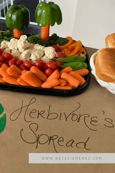 a tray filled with vegetables and bread on top of a cardboard box next to a sign that says herbivoe's spread