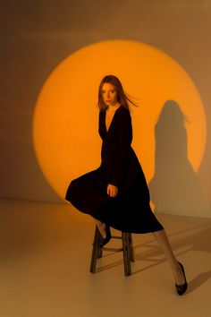 a woman is sitting on a chair in front of a large sun