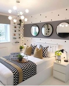 a bedroom with three round mirrors on the wall and black and white decor around the bed