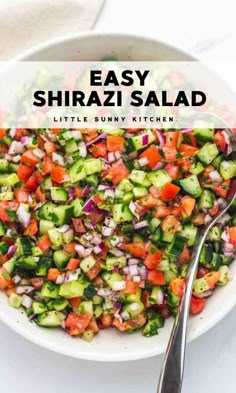 a white bowl filled with cucumber, red onion and tomato salad next to a spoon