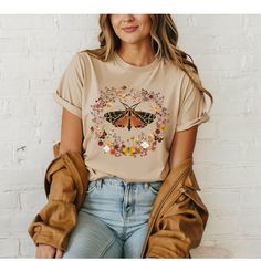 Introducing our newest addition: the Boho Butterfly Shirt, adorned with mushrooms, bumblebees, painted flowers, and real pressed flowers. This T-shirt combines art and nature to create a unique design. Crafted from 100% organic ring-spun cotton, this unisex tee offers comfort and breathability. Whether you're strolling through a meadow, enjoying a serene afternoon in the city, this shirt is designed to keep you comfortable and stylish. Perfect for eco-conscious fashion enthusiasts and sustainabl Casual Mushroom Print T-shirt For Spring, Casual Butterfly Print Shirt For Spring, Casual Fall Shirt With Plant Print, Summer Short Sleeve Tops With Mushroom Print, Casual Plants Print T-shirt For Fall, Spring Butterfly Print Crew Neck Shirt, Casual T-shirt With Plants Print For Fall, Casual Fall T-shirt With Plant Print, Casual Cotton Shirt With Butterfly Print