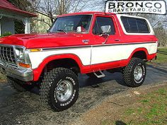 a red and white truck is parked in front of a house with the words bronco on it