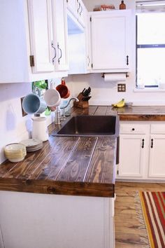 a kitchen with white cabinets and wooden counter tops