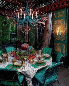 an outdoor dining area with green chairs and a chandelier