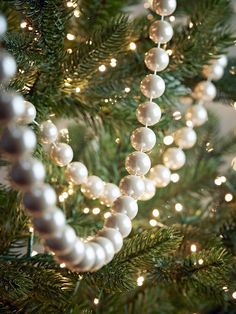 a close up of a christmas tree with lights and beads hanging from it's branches