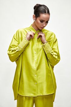 Lime green button down asymmetric shirt with detailed broad pearl embroidered cuffs and pleated detailing at back. Paired with pant.
Components: 2
Pattern: Embroidered
Type Of Work: Pearl
Neckline: Shirt collar
Sleeve Type: Bishop
Fabric: Silk blend
Color: Green
Other Details: 
Button placket
Embroidered cuffs
Asymmetric detailing
Occasion: Party - Aza Fashions Elegant Summer Blouse With Embroidered Cuffs, Green Blouse With Button Cuffs For Daywear, Elegant Green Tops With Button Cuffs, Elegant Green Blouse With Button Cuffs, Pearl Shirt, Asymmetric Shirt, Embroidered Cuffs, Green Button, Fabric Silk