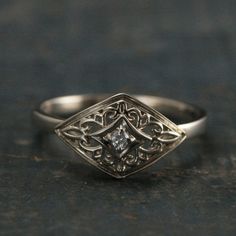 a close up view of a ring on a black surface with a diamond in the center