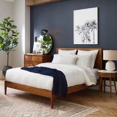 a bed room with a neatly made bed next to a night stand and two tables