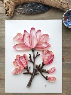 pink flowers on white paper next to driftwood