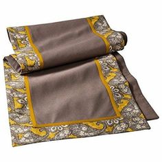 a yellow and grey paisley print blanket folded on top of each other with an orange border