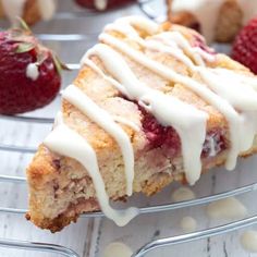 a piece of cake with icing and strawberries on the side