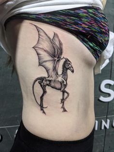 a woman's stomach with a black and white dragon tattoo on her side ribcage