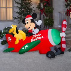 mickey mouse and pluto on an airplane in front of a house decorated with christmas decorations