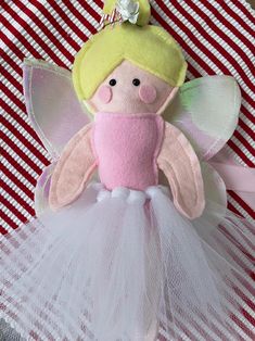 a pink and green fairy doll with white tutule on a red and white checkered tablecloth