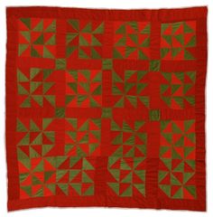 a red and green quilt with small squares on the bottom, one square has an arrow at the center