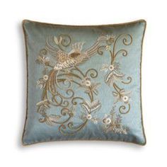 a blue pillow with an embroidered bird and flowers design on it's front side