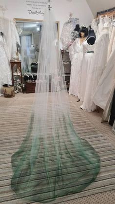 a wedding dress is on display in a bridal room with veils hanging from the ceiling