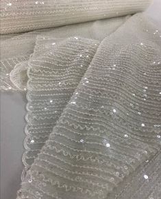 white sequins on sheer fabric, with some shiny beads in the middle and bottom