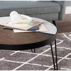 a coffee table with magazines and headphones on it in front of a gray couch