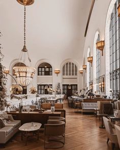 a large room filled with lots of furniture and tall windows next to a christmas tree