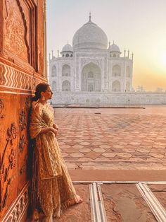 a woman leaning against a wall in front of the tajwa mosque, india