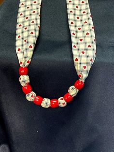 a red beaded necklace with hearts on it sitting on top of a black bag