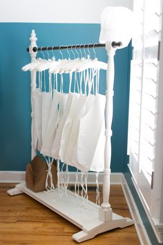 an ironing board with white clothes hanging from it's sides in front of a blue wall