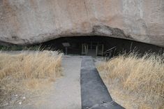 an entrance to a cave in the side of a mountain with grass growing on it