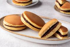 some cookies are sitting on a plate and one is cut in half to look like sandwiches