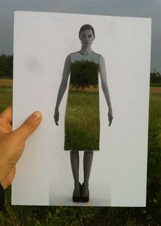 a hand holding up a photo of a woman's body with grass in the background