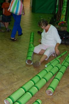 a woman sitting on the floor surrounded by green pipes