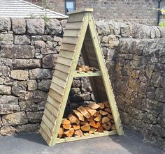 a pile of wood sitting in front of a stone wall next to a wooden structure