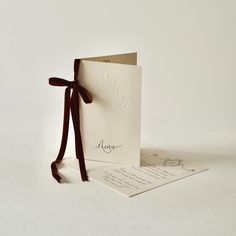 a white card with a brown ribbon tied around it