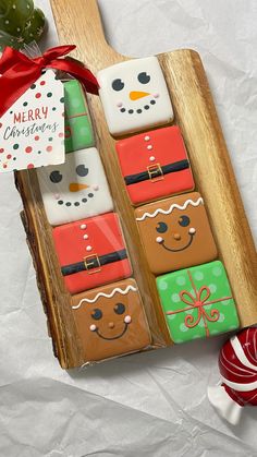 decorated cookies in the shape of snowmen are on a wooden tray next to candy canes