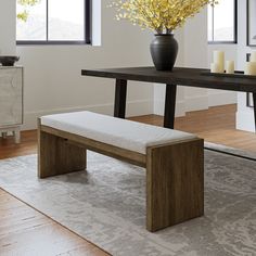 a wooden bench sitting next to a table with a vase on it and candles in the background