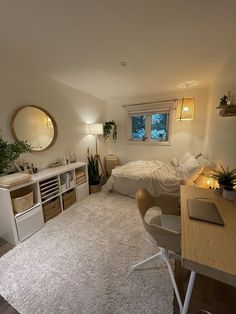 a bedroom with a bed, desk and mirror in it's corner next to a window