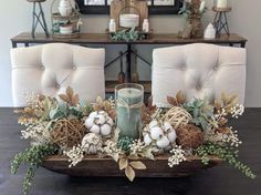 a centerpiece with candles and greenery sits on a dining room table