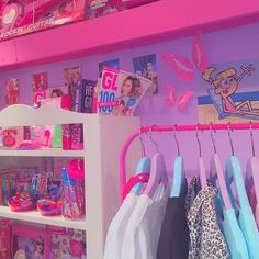 there is a pink and purple room with clothes hanging on the rack in front of it