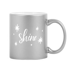 a silver coffee mug with the word shine written in white ink on it and snowflakes