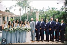 a group of people standing next to each other in front of a pool and palm trees