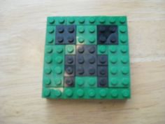 a small green lego block sitting on top of a wooden table