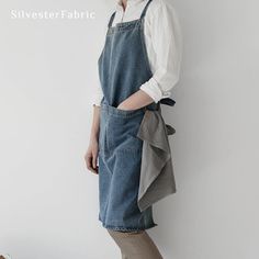 a woman standing in front of a white wall wearing overalls and a denim dress